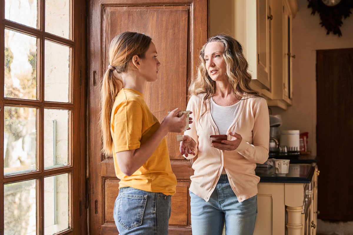 Mother and teen daughter having a quiet conversation in the kitchen